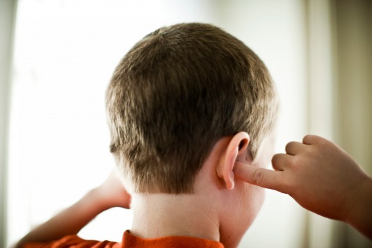 Back view of boy (6-7 years) covering ears