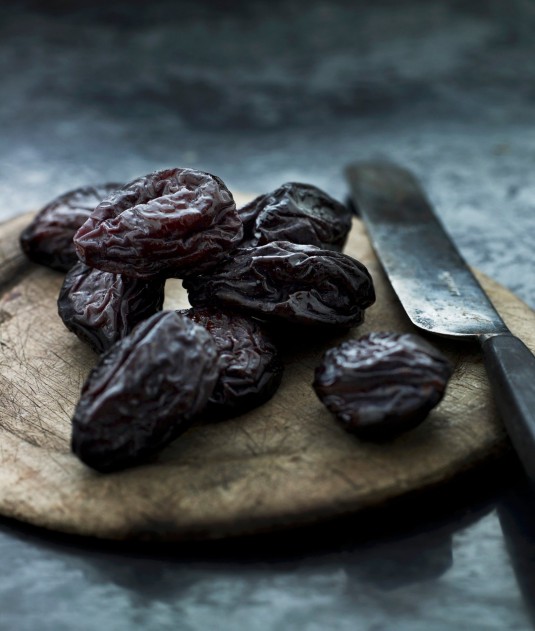 Prunes on a wooden board with a knife